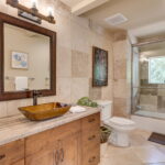 Remodeled full bath with custom cabinets and travertine stone.