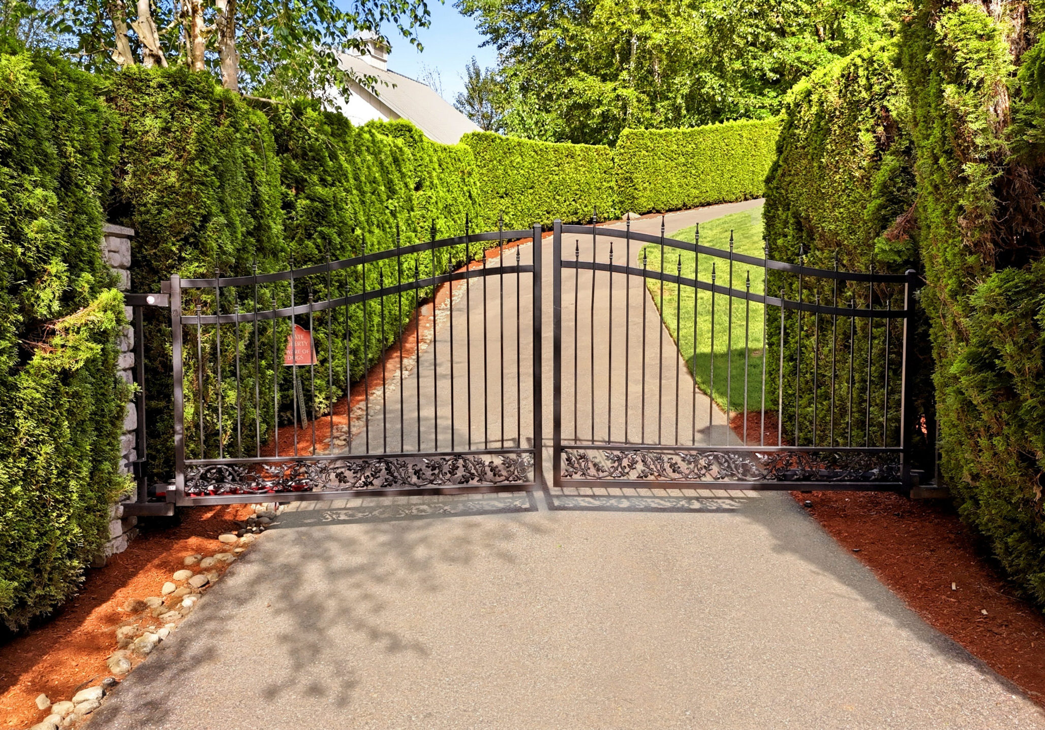 Wrought-iron gate across tree-lined driveway